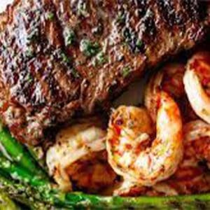 A steak and shrimp dinner with asparagus.